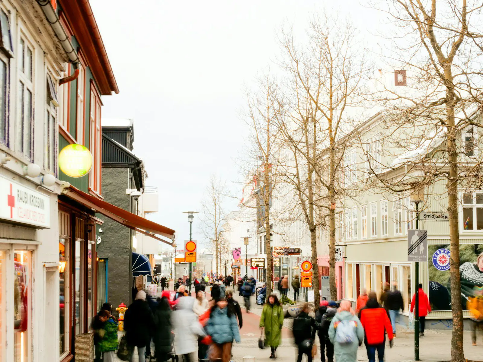 a group of people walking down a street next to tall buildings